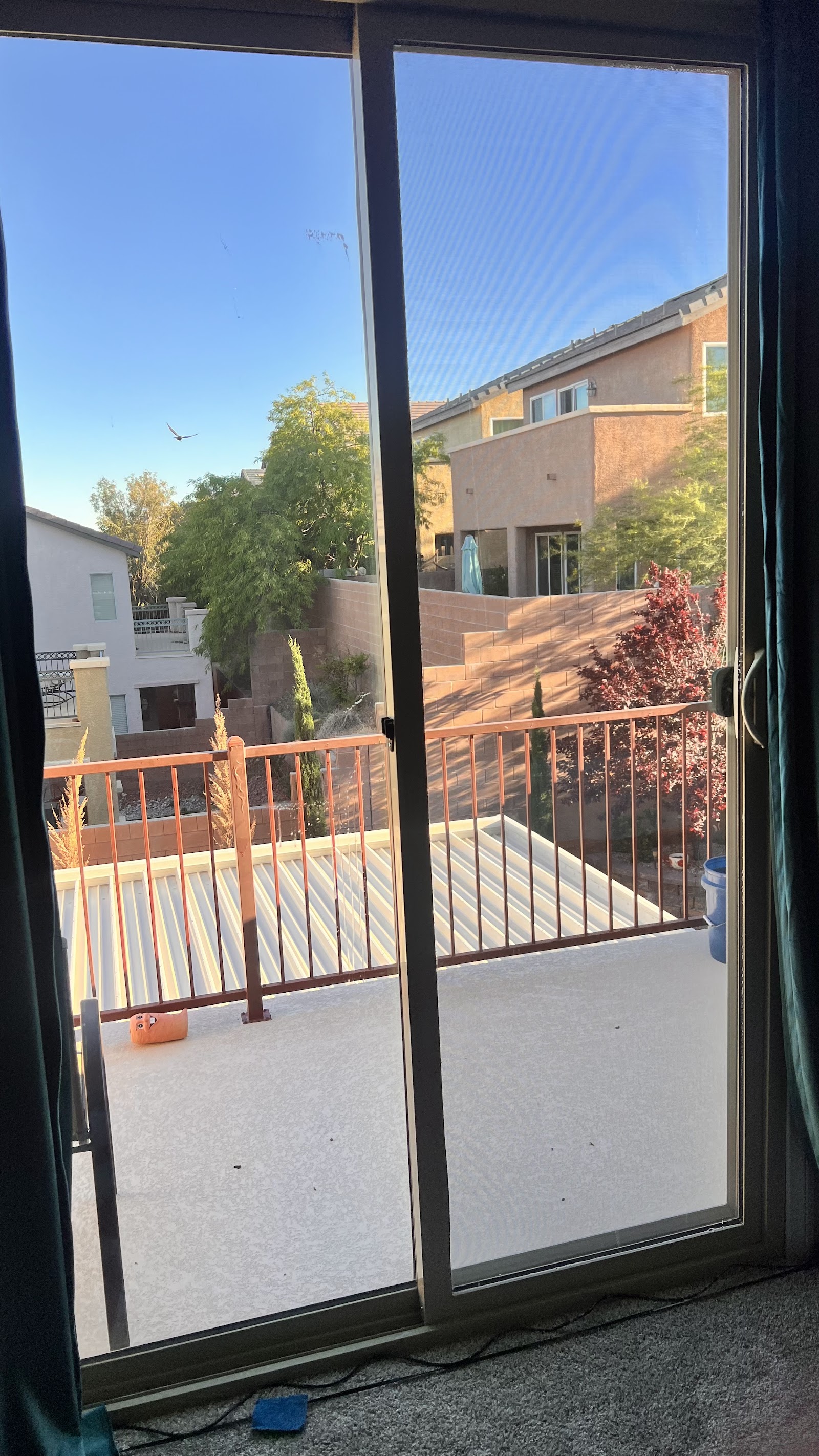 Residential sliding glass door with window tint film applied, view of backyard